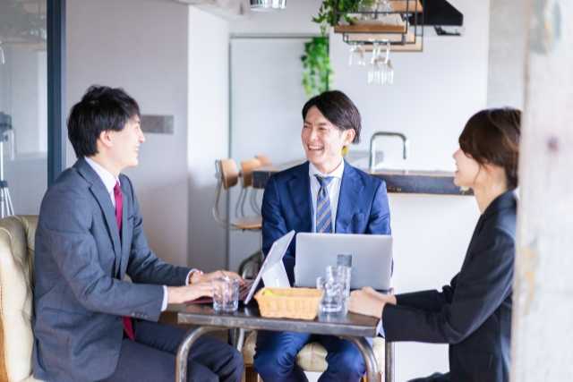 カフェで談笑しながら仕事をする3人の会社員